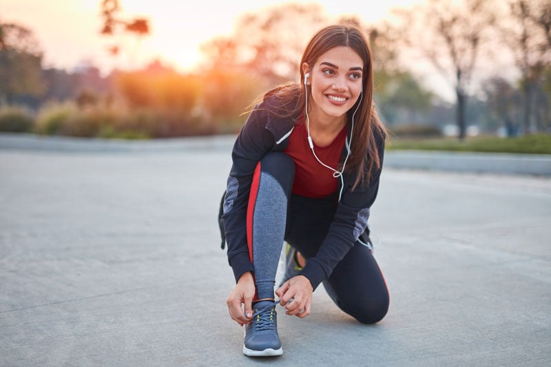 young-woman-tying-running-shoes-in-park