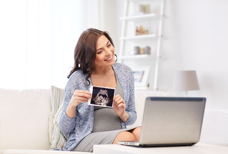 happy-woman-sharing-ultrasound-picture-over-laptop