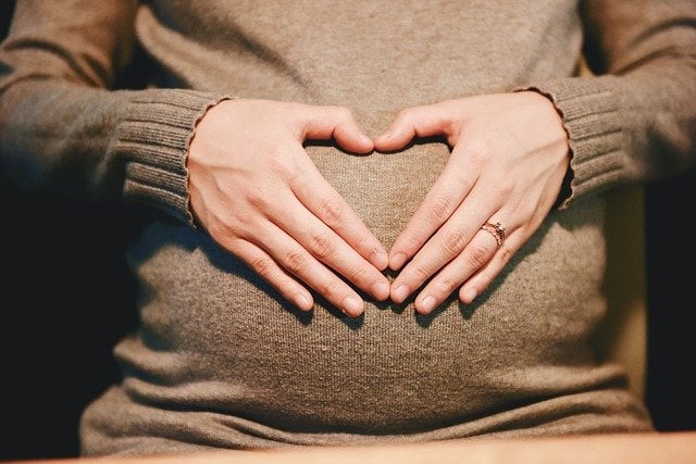 Pregnant woman with a heart shaped hand on her belly